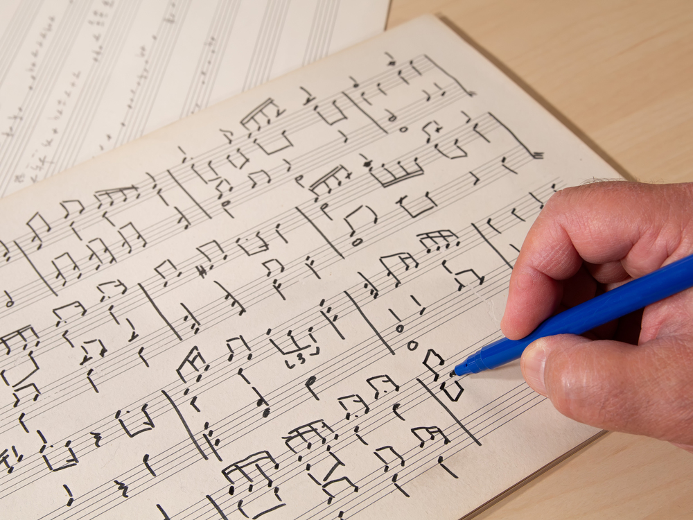 Compositore che scrive musica su uno spartito